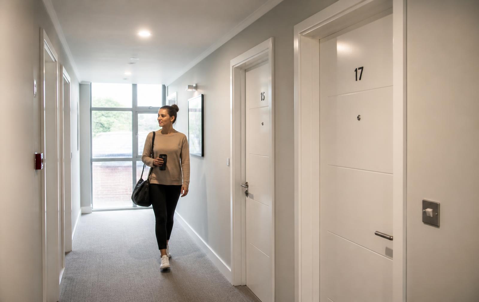 Resident walking through the bright communal hallway of a modern block of flats